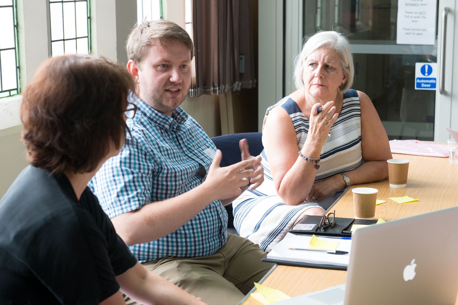 Adults sit around a table discussing