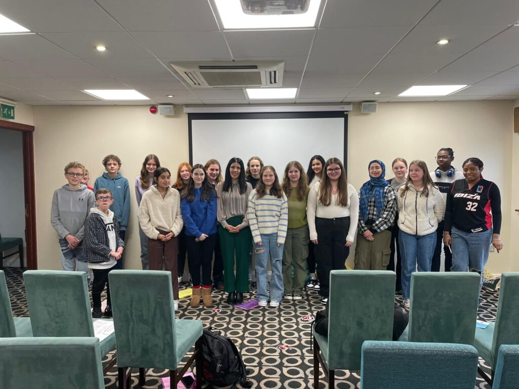 A group of young people and the Children's Commissioner are stood together smiling for a photograph